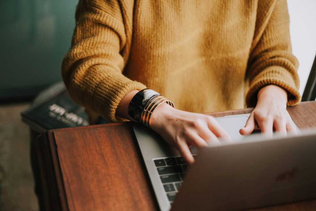Person in a yellow jumper on a laptop