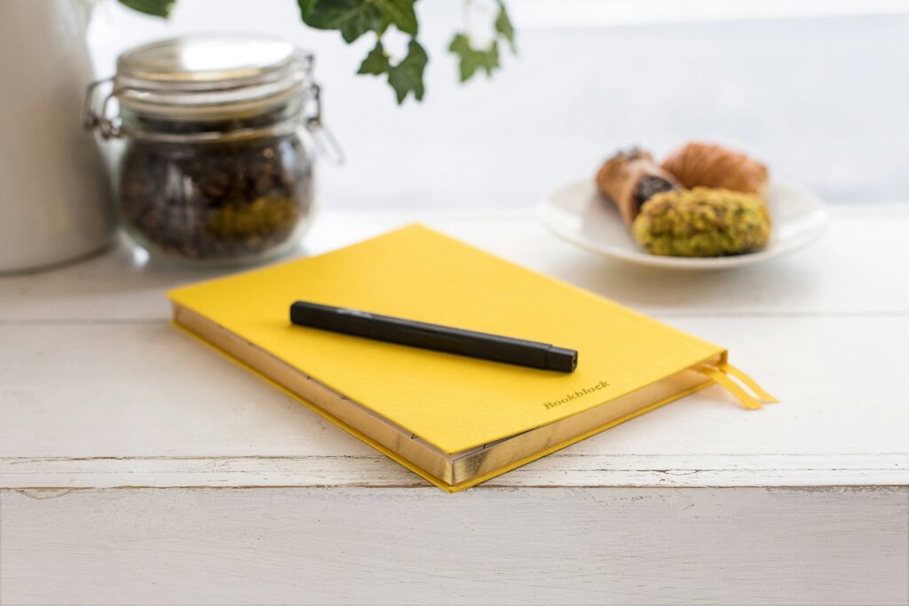 Yellow notebook with a pen resting on top