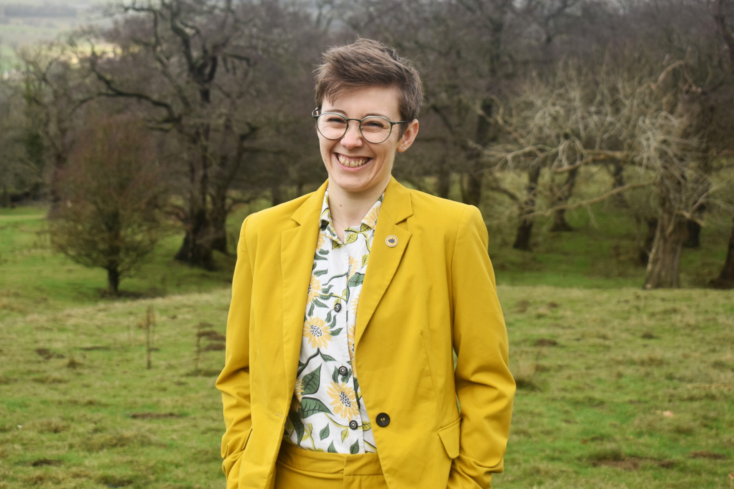Photo of Tee in a yellow suit laughing at the camera