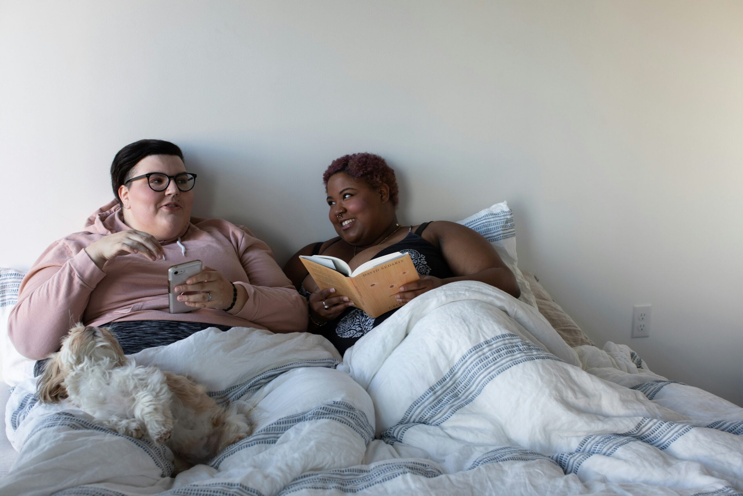 Queer couple reading in bed